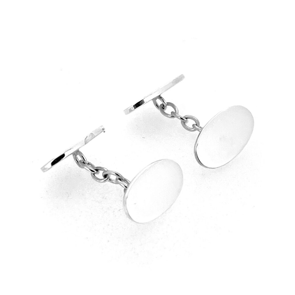 Oval silver cufflinks with Celtic Revival inspired engraving and traditional connecting chains